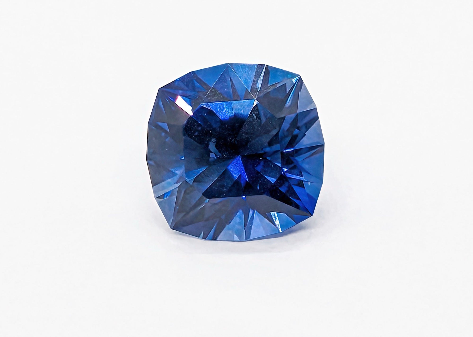A loose blue sapphire photographed on a pale background.