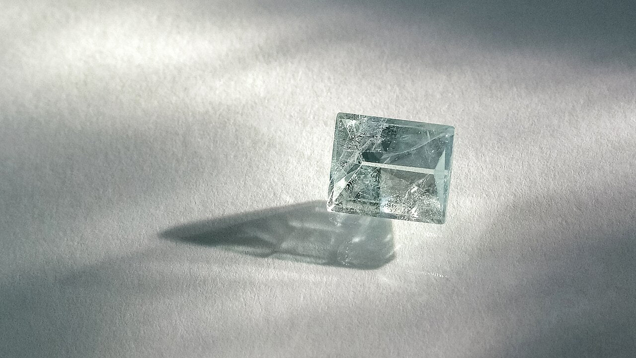 A pale blue-green rectangular aquamarine casting a long shadow
