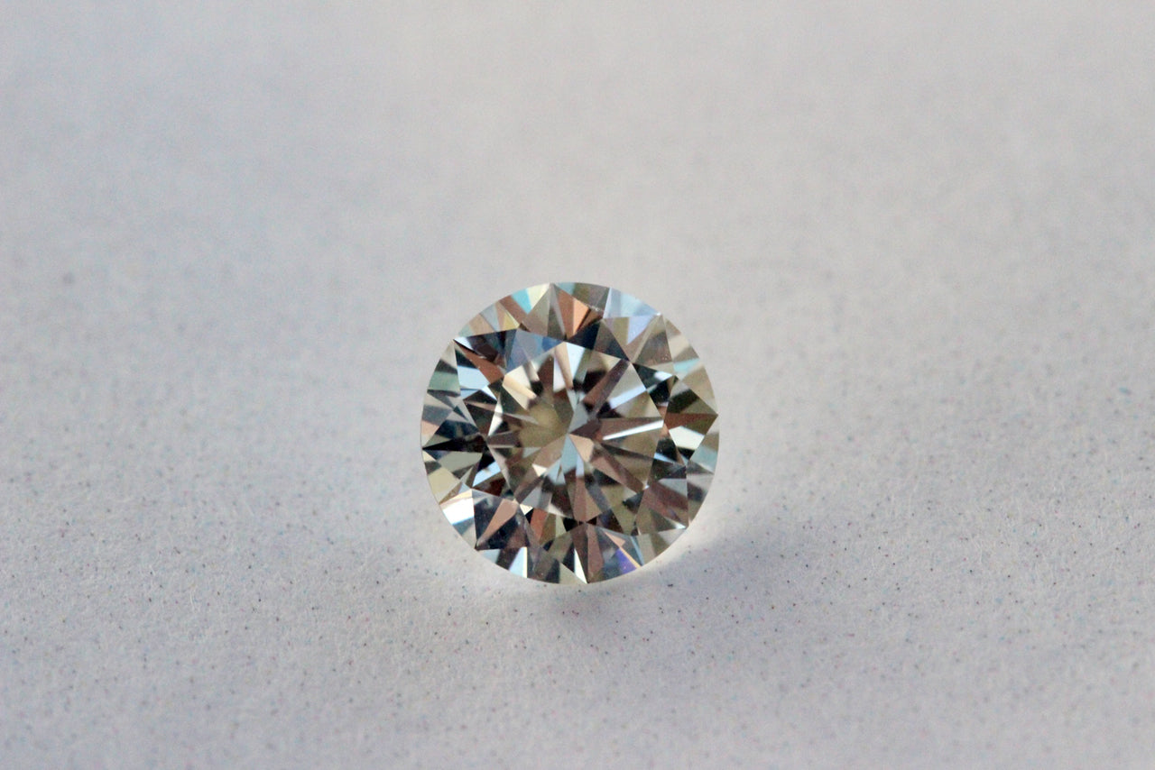 A loose round brilliant diamond on a pale surface